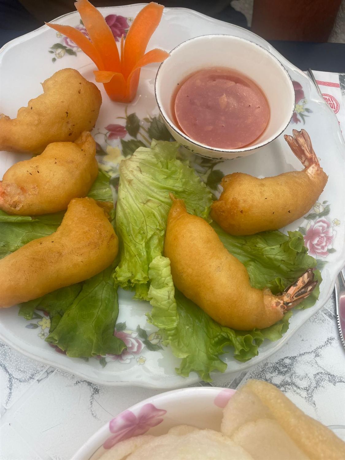 Beignets de crevettes dorés avec sauce, carotte sculptée et salade