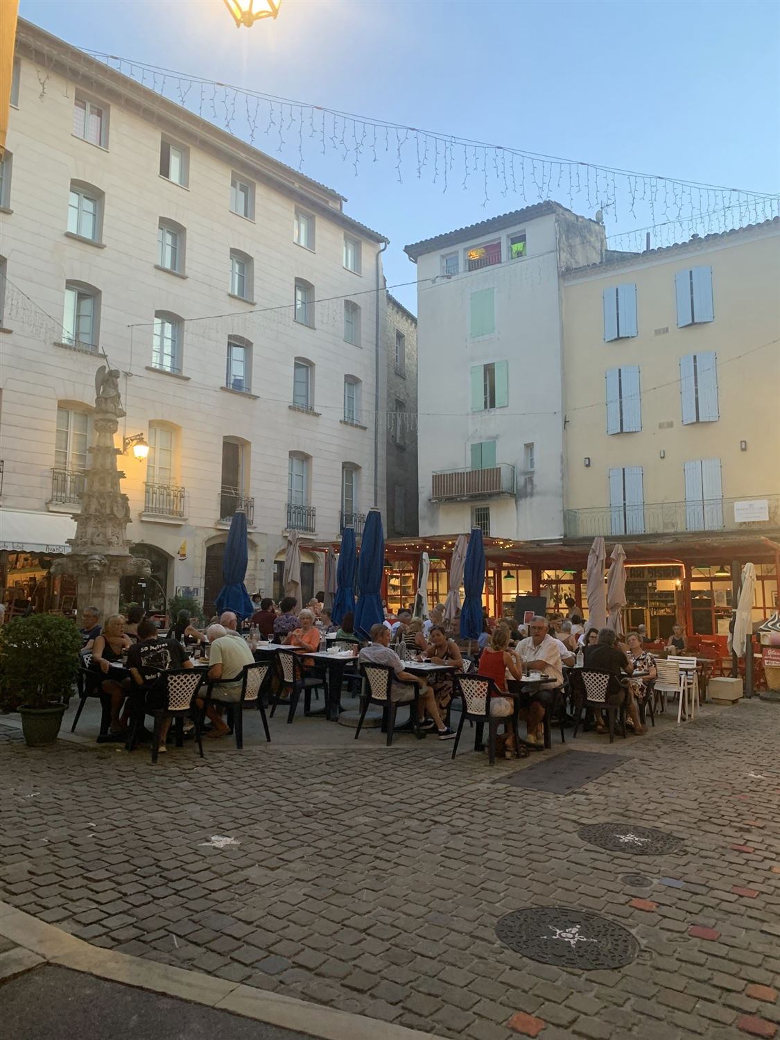 La place Saint-Michel à Forcalquier au crépuscule, avec les tables de la terrasse