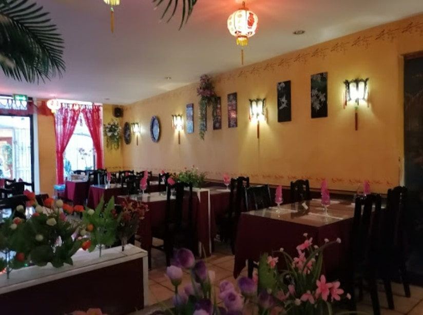 La salle du restaurant Le Saigon : murs ocre, nappes bordeaux et lanternes rouges