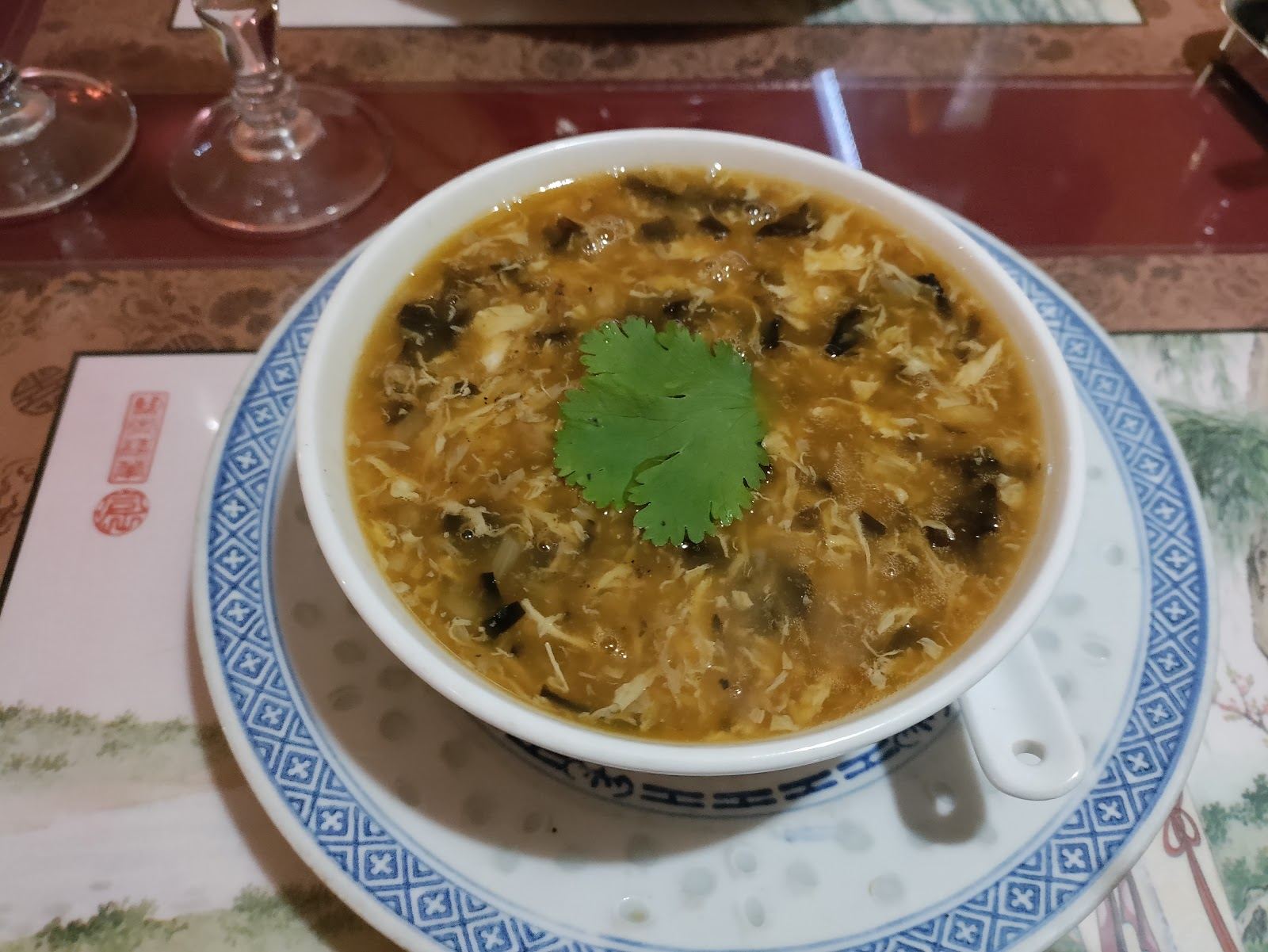 Soupe fumante garnie de coriandre dans un bol bleu et blanc